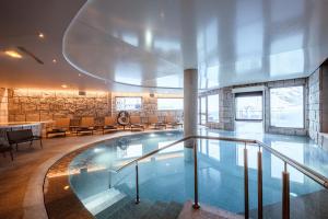 a large swimming pool in a building with chairs at Altapura in Val Thorens