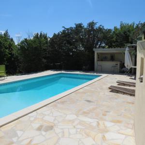 a swimming pool with a stone patio and blue water at Mas Myro in Uzès