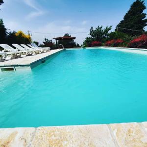 una gran piscina con sillas y cenador en Casa privata immersa nel verde con giardino e piscina, ad Assisi, en Mora