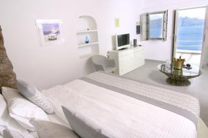 a white bedroom with a bed and a television at Vogue Suites in Oia
