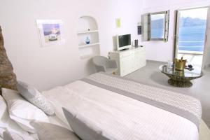 una camera bianca con letto e televisore di Vogue Suites a Oia