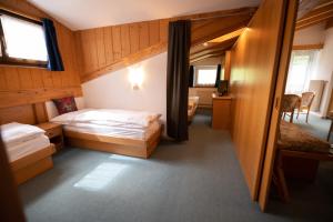 a hotel room with two beds and a desk at Appartamenti Arnica in Alba di Canazei