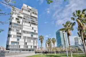 a tall building with palm trees in front of it at Alcam Llum Deluxe in Barcelona
