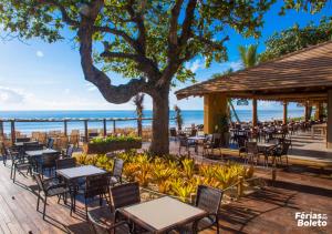 um restaurante na praia com mesas e cadeiras em PSP Resort All Inclusive em Porto Seguro