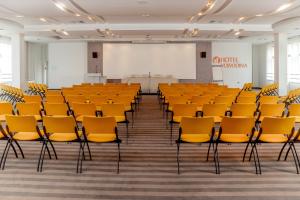 an empty lecture hall with yellow chairs and a whiteboard at Hotel Vojvodina in Zrenjanin