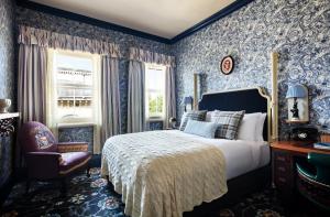 a bedroom with blue walls and a bed and a chair at The Randolph Hotel, by Graduate Hotels in Oxford