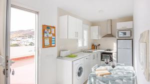 eine weiße Küche mit Waschmaschine und Tisch in der Unterkunft María Carmona - Casa Daniela 2 Níjar by Ruralidays in Níjar