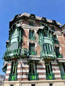 um edifício alto com janelas verdes e brancas em L'appartement Mersois - 50m de la mer & cosy em Mers-les-Bains