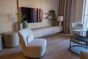 uma sala de estar com cadeiras, uma televisão e uma mesa em The Harbour luxurious, use of hotel swimming pool and sauna em Cadzand
