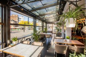 ein Restaurant mit Tischen, Stühlen und Pflanzen in der Unterkunft Golden Tulip Hotel Central in ’s-Hertogenbosch