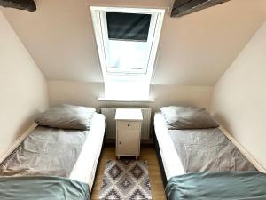 two beds in a small room with a window at Cozy one bedroom apartment near the sea in Tisvildeleje