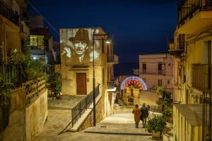 Un groupe de personnes marchant dans une rue la nuit dans l'établissement B&B Antico Caricatore - Ex B&B Porta di Mare, à Sciacca