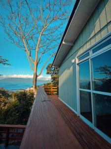 una pasarela de madera junto a una casa con un árbol en GREEN HOUSE - com linda vista para o mar, en Palhoça