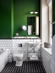 a green and white bathroom with a toilet and a sink at The Randolph Hotel, by Graduate Hotels in Oxford