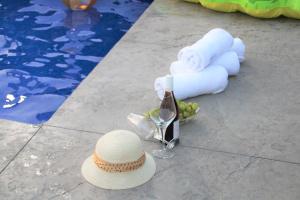 a straw hat and a glass of wine and towels at Refael Garden Villa 