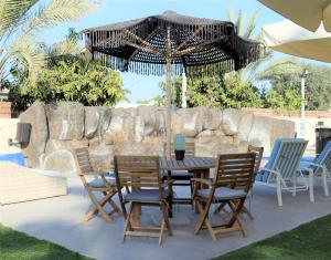 a table and chairs under an umbrella on a patio at Refael Garden Villa 
