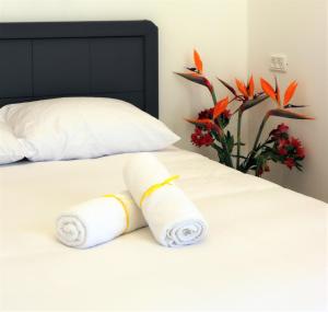two rolled towels on a bed with a vase of flowers at Refael Garden Villa 