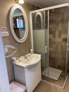 a bathroom with a sink and a shower with a mirror at Pensiunea Tinelu Brașov sacele in Braşov