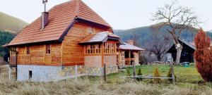 una casa de madera en un campo con montañas en el fondo en Kuca Karajic, en Užice