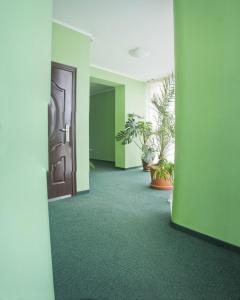 um corredor com paredes verdes e uma porta e plantas em Motel em Ivano-Frankivsk