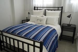 un letto con coperta e cuscini a righe blu e bianche di Nature's Rest a Città del Capo