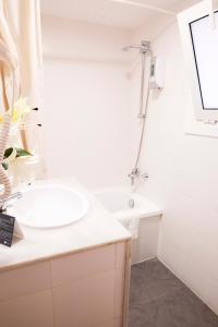 a white bathroom with a sink and a shower at Hotel Subur in Sitges