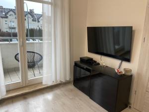 a living room with a flat screen tv and a window at Modern Box Apartment in Gdynia