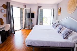 a bedroom with two beds and two large windows at Hotel Subur in Sitges