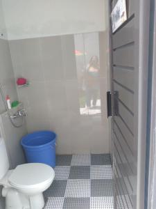 a bathroom with a toilet and a blue bucket at Villa Adinda Syariah D6 in Tarogong