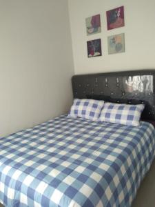 ein Schlafzimmer mit einem blau-weißen karierten Bett in der Unterkunft Villa Adinda Syariah D8 in Tarogong