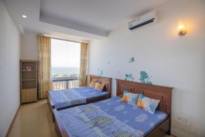 two beds in a room with a window at Sơn Thịnh - Oasky Apartment in Vung Tau