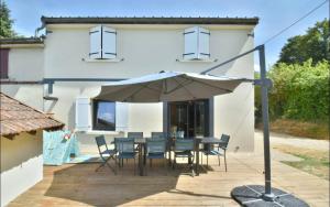 een patio met een tafel en stoelen en een parasol bij La Maison du Bonheur in Lons-le-Saunier