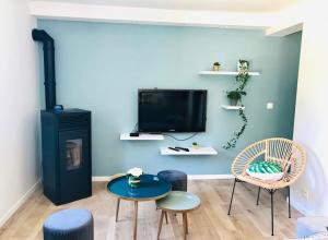 een woonkamer met een tv en een tafel en stoelen bij La Maison du Bonheur in Lons-le-Saunier