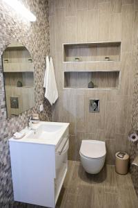 een badkamer met een wastafel, een toilet en een spiegel bij Роял Шумен in Shumen