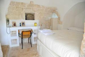 1 dormitorio con 1 cama y 1 mesa con silla en Tenuta Bianca with amazing exclusive pool, en Ostuni
