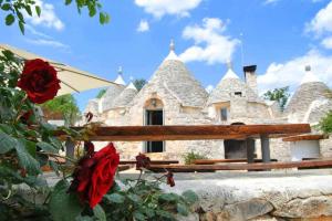 una casa de piedra con rosas rojas delante de ella en Tenuta Bianca with amazing exclusive pool, en Ostuni