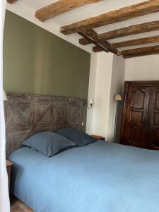 sypialnia z niebieskim łóżkiem z drewnianym zagłówkiem w obiekcie Château de Nazelles Amboise w mieście Nazelles