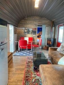 a living room with a couch and red chairs at Gleis 2, Waggon mit Ofen, Whirlpool und Sauna in Dahlem