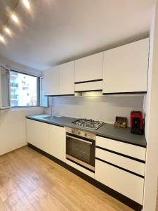 una cucina con mobili bianchi e un forno a piano cottura di Casetta di Gaia a Monopoli