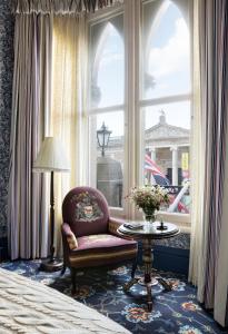 a living room with a chair and a table and a window at The Randolph Hotel Oxford, a Graduate by Hilton Hotel in Oxford