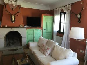 a living room with a white couch and a fireplace at Casa Rural de la Finca Sierra Grande in Hornachos
