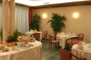 ヴィットリオ・ヴェネトにあるAlbergo Ristorante Floraのテーブルと椅子(白いテーブルクロス付)が備わるレストラン