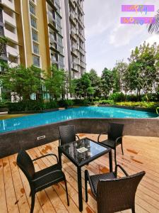 a patio with chairs and a table and a pool at Legoland-HappyMoonlight-2BR-7px- GardenPoolview with Wifi in Nusajaya