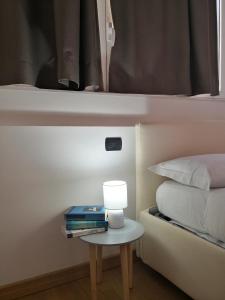 a table with a lamp and books on it next to a bed at Loft ristrutturato vicino M4 Argonne - San Benigno in Milan