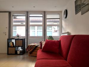 a living room with a red couch and two windows at Loft ristrutturato vicino M4 Argonne - San Benigno in Milan