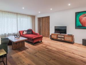 a living room with a red couch and a flat screen tv at DasBeckHaus - Chiemgau Karte in Inzell