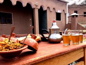 uma mesa com uma tigela de comida e dois copos de cerveja em Gite entre les deux Vallées em Tacheddirt