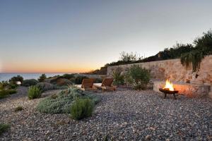 a fire pit with two benches on a beach with the ocean at Villa Vito in Hvar