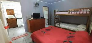 um quarto com 2 beliches e uma cama vermelha em Casinha de hóspedes aconchegante. em São Sebastião