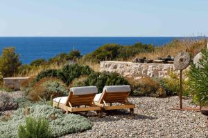 two chairs sitting on the gravel near the ocean at Villa Vito in Hvar